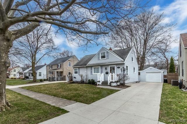 bungalow featuring concrete driveway, a residential view, a front lawn, an outbuilding, and a garage