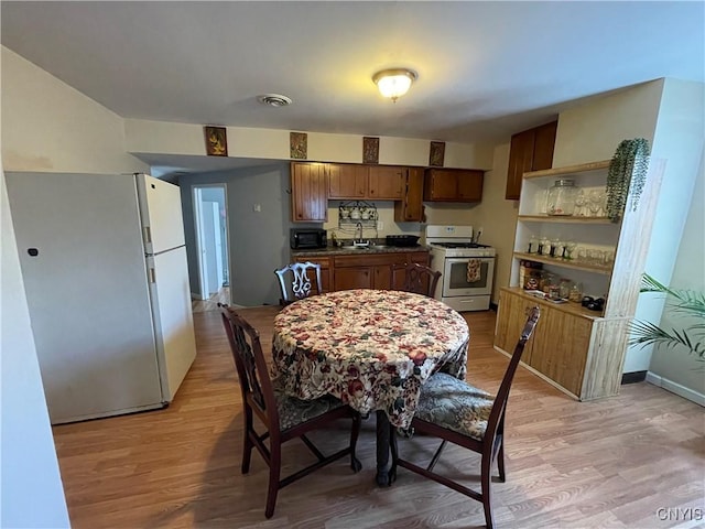 422 N James St, Rome-Inside, NY 13440 - kitchen featuring light wood-style floors, white appliances, visible vents, a sink, and dark countertops