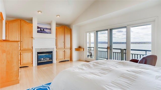 367 Waters Edge, Owasco, NY 13021 - bedroom featuring access to exterior, vaulted ceiling, a water view, a fireplace, and light wood-style floors
