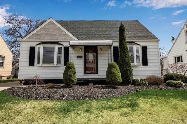 view of front facade featuring roof with shingles and a front lawn