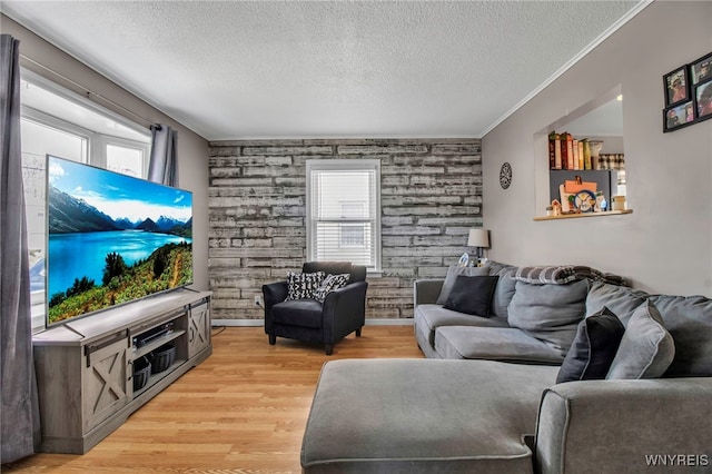 living room featuring a textured ceiling, crown molding, plenty of natural light, and light wood-style floors