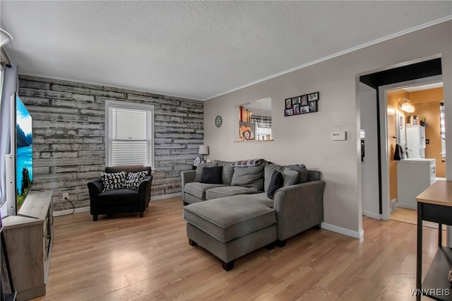living area with light wood-type flooring, an accent wall, a textured ceiling, and ornamental molding