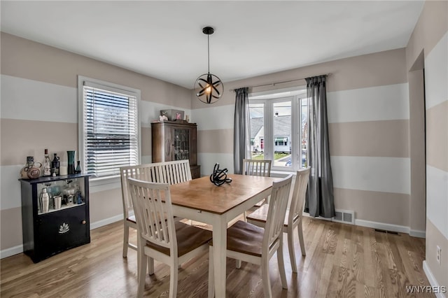 dining room with light wood-style floors, a healthy amount of sunlight, and visible vents