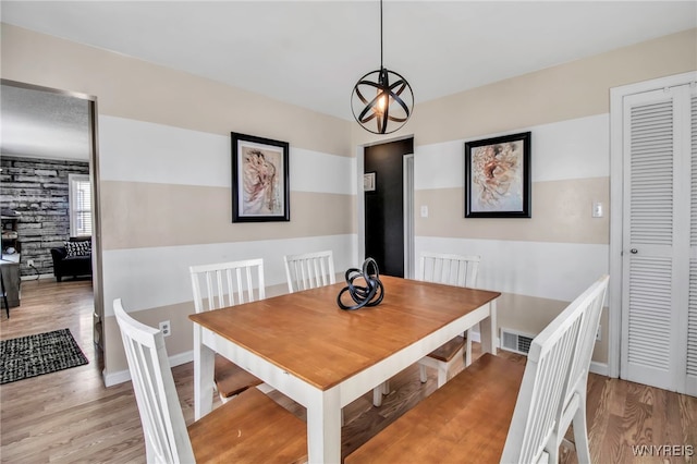 dining area with a chandelier, wood finished floors, baseboards, and visible vents