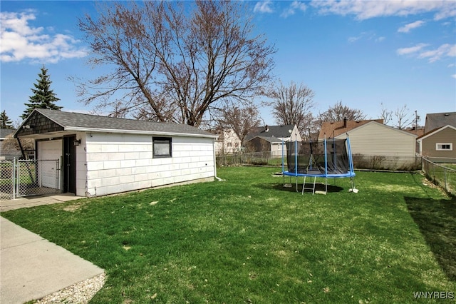 view of yard with an outbuilding, a fenced backyard, a trampoline, and a detached garage