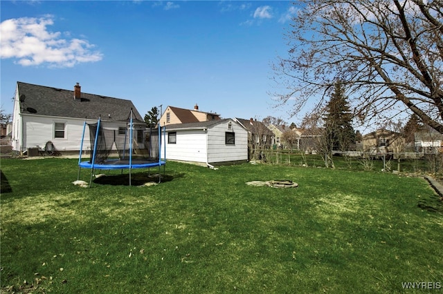 view of yard featuring an outdoor structure, an outdoor fire pit, fence, and a trampoline
