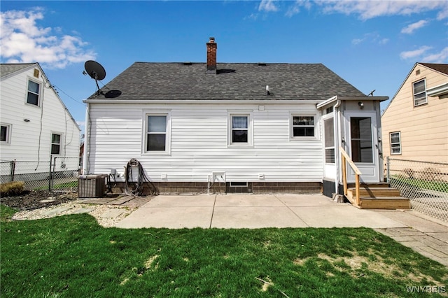 back of property with central air condition unit, a chimney, a lawn, fence, and a shingled roof