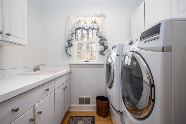 5572 Lakewood Trl, South Bristol, NY 14424 - laundry area with light wood-style flooring, separate washer and dryer, visible vents, a sink, and cabinet space