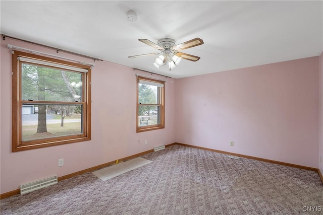 empty room with visible vents, baseboards, a ceiling fan, and a healthy amount of sunlight