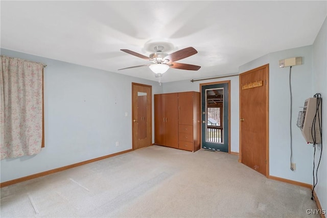 unfurnished bedroom with baseboards, light colored carpet, heating unit, and ceiling fan
