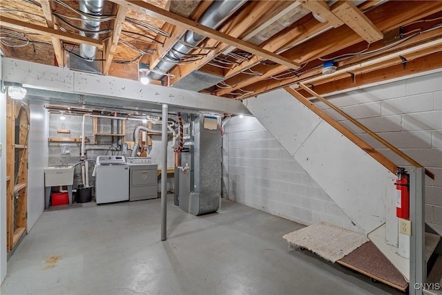 unfinished basement with a sink, washing machine and clothes dryer, and heating unit