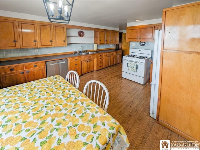 kitchen with a sink, decorative backsplash, white appliances, and wood finished floors