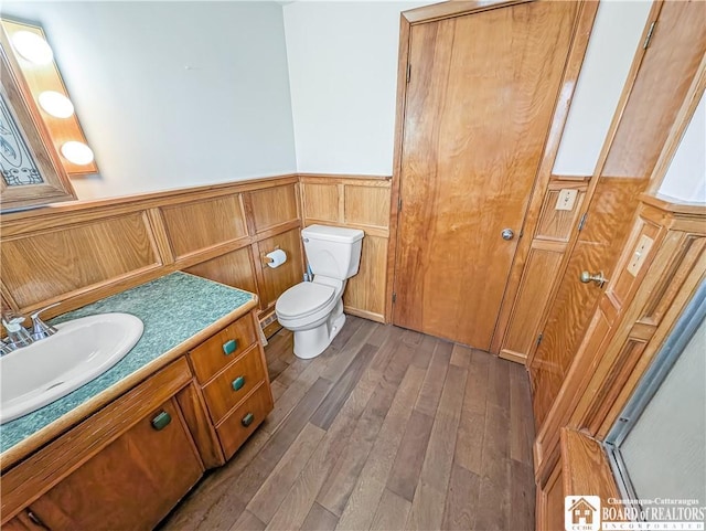 bathroom featuring toilet, vanity, wainscoting, and hardwood / wood-style flooring