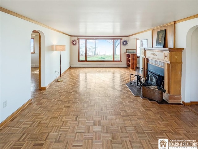unfurnished living room with arched walkways, baseboard heating, baseboards, and crown molding