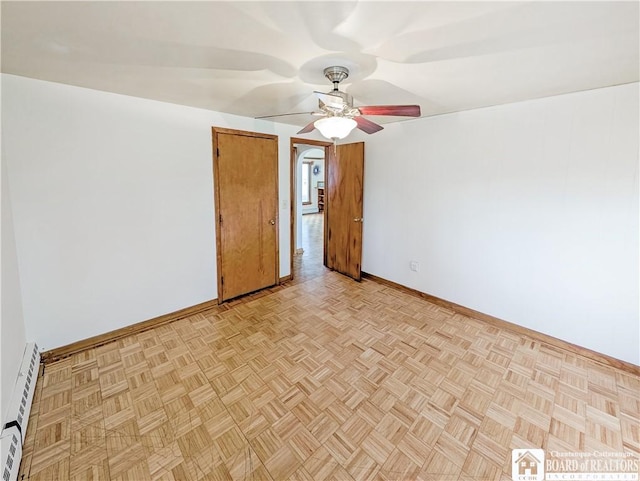 unfurnished room with ceiling fan, a baseboard heating unit, and baseboards