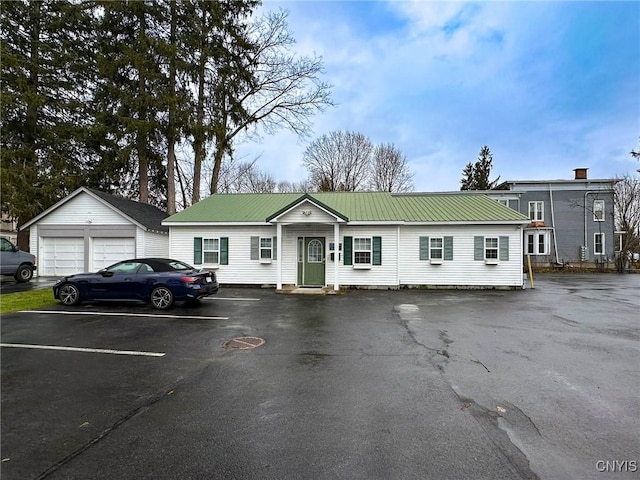 view of front of home featuring an outdoor structure, metal roof, and uncovered parking