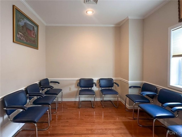 sitting room with crown molding, wood finished floors, baseboards, and plenty of natural light