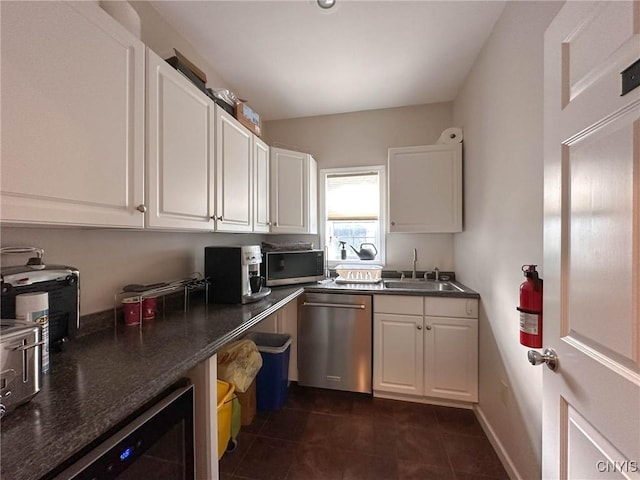 kitchen with a sink, white cabinets, appliances with stainless steel finishes, and dark tile patterned floors