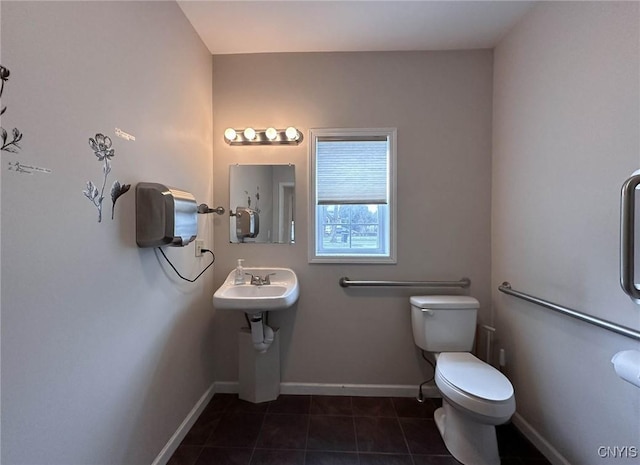 bathroom with toilet, tile patterned floors, baseboards, and a sink