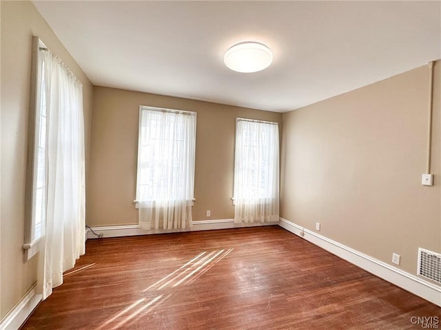 spare room with wood finished floors, baseboards, and visible vents