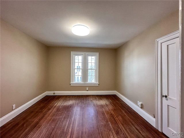 unfurnished room featuring dark wood-style floors and baseboards