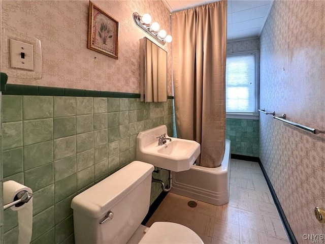 bathroom featuring wallpapered walls, tile patterned floors, toilet, wainscoting, and a sink