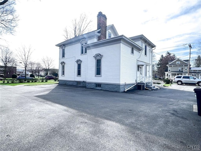 view of side of home with entry steps and a chimney