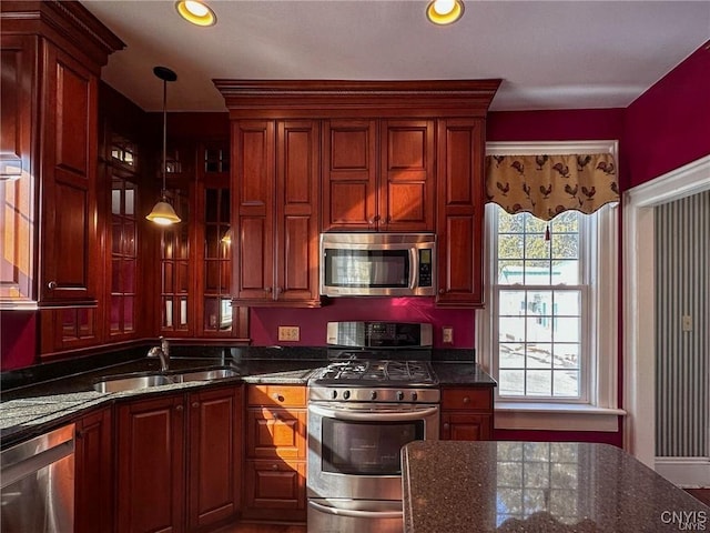 kitchen with a sink, pendant lighting, appliances with stainless steel finishes, and dark stone countertops