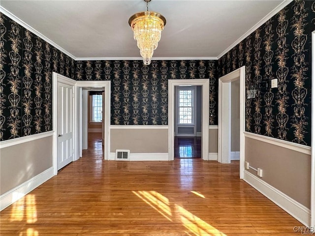 spare room with visible vents, baseboards, hardwood / wood-style floors, and a chandelier