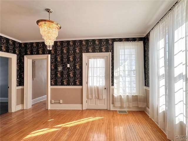 interior space featuring a healthy amount of sunlight, light wood finished floors, wainscoting, and an inviting chandelier