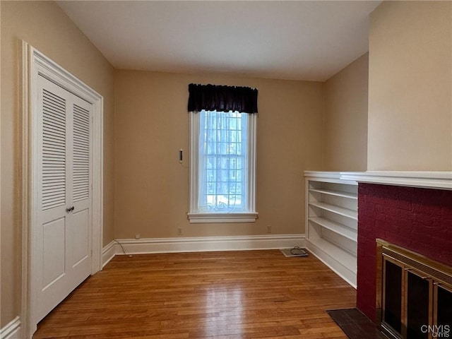 unfurnished living room featuring a fireplace, visible vents, baseboards, and wood finished floors
