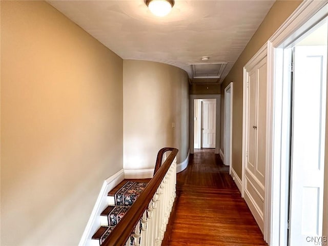 corridor with dark wood-type flooring, attic access, baseboards, and an upstairs landing