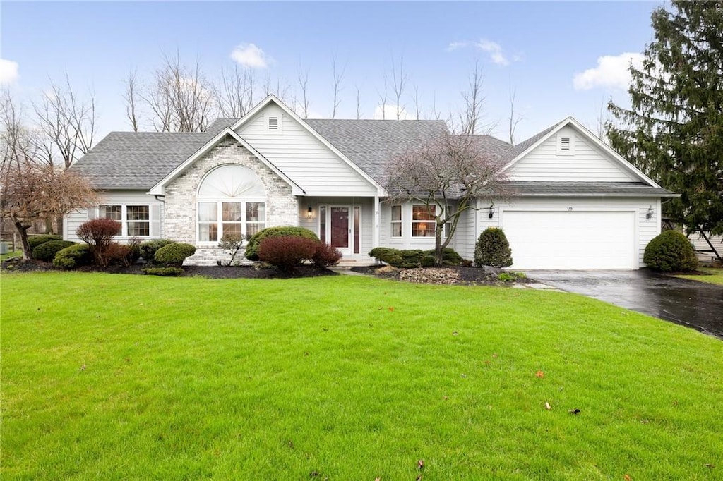 view of front of house featuring roof with shingles, stone siding, a front lawn, aphalt driveway, and a garage
