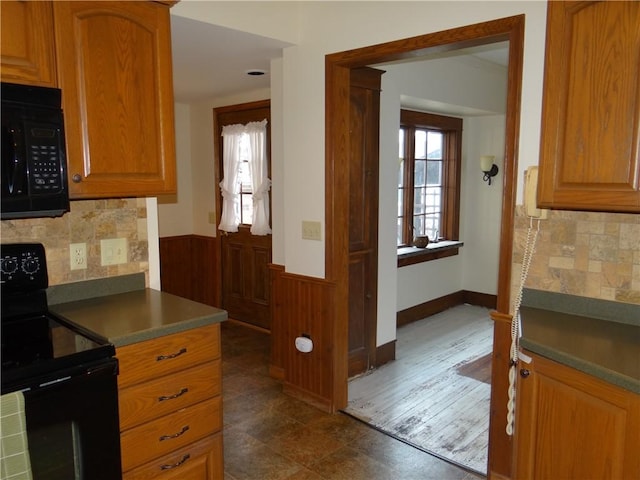 956 Hoffman St, Elmira-City, NY 14905 - kitchen featuring tasteful backsplash, black appliances, wainscoting, brown cabinets, and wooden walls