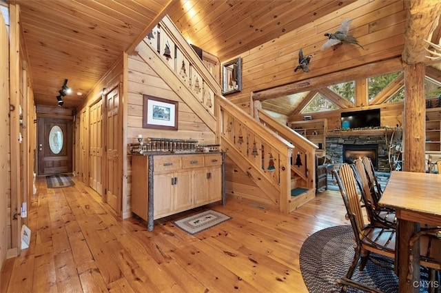 kitchen with wooden walls, light wood-type flooring, wooden ceiling, and dark countertops