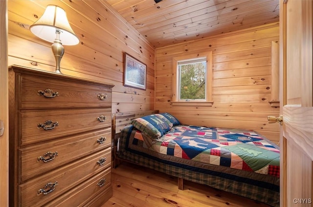 bedroom featuring wooden walls, light wood-style flooring, and wooden ceiling