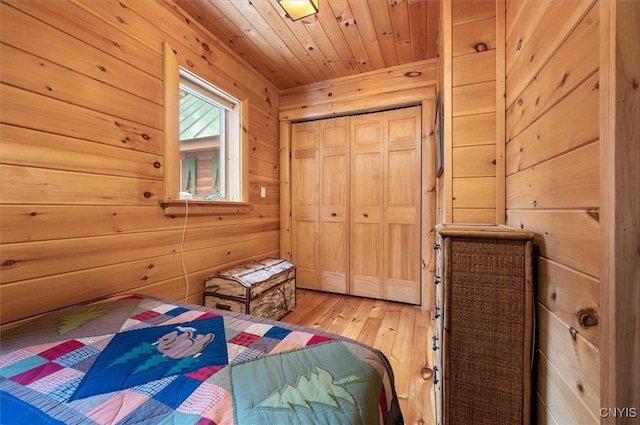 bedroom with a closet, wooden walls, light wood-style floors, and wood ceiling
