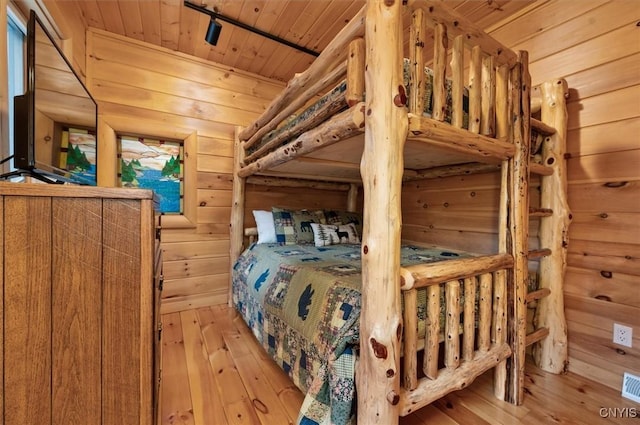 bedroom with wooden walls, visible vents, light wood-type flooring, and wooden ceiling