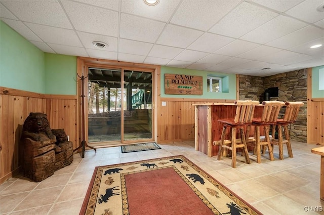 bar with wood walls, a drop ceiling, and visible vents