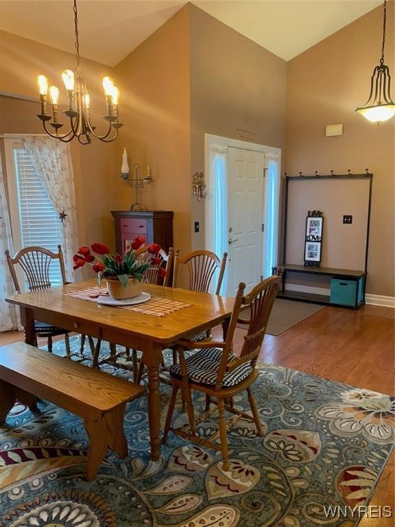 253 Glenvale Rd, Porter, NY 14174 - dining area with high vaulted ceiling, a notable chandelier, baseboards, and wood finished floors