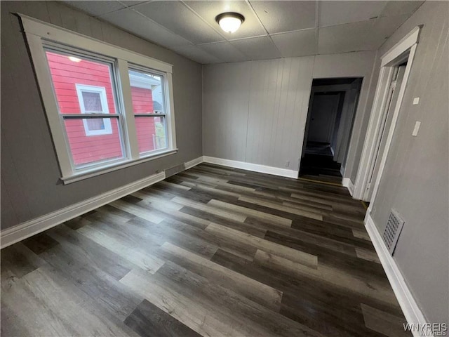 spare room with wood finished floors, baseboards, a drop ceiling, and visible vents