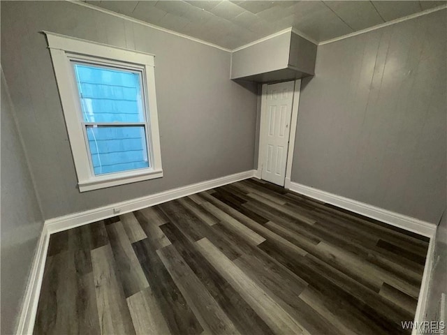 spare room with dark wood-style flooring, baseboards, and ornamental molding