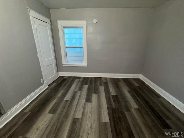 empty room with baseboards and dark wood finished floors