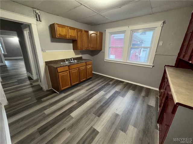 kitchen with brown cabinets, a paneled ceiling, baseboards, and dark wood-style floors