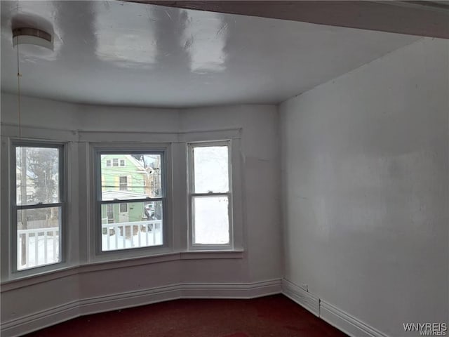 unfurnished room with dark colored carpet and baseboards