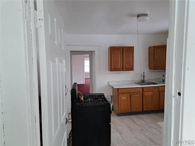 kitchen with a sink, light countertops, black gas stove, and brown cabinets