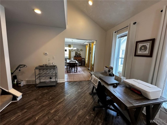 office space with visible vents, vaulted ceiling, wood finished floors, baseboards, and a notable chandelier