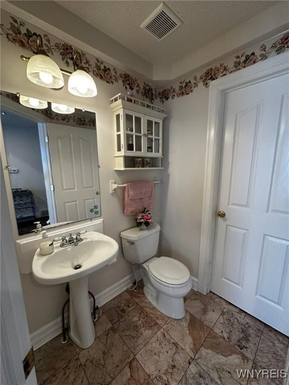 bathroom with visible vents, toilet, marble finish floor, and baseboards