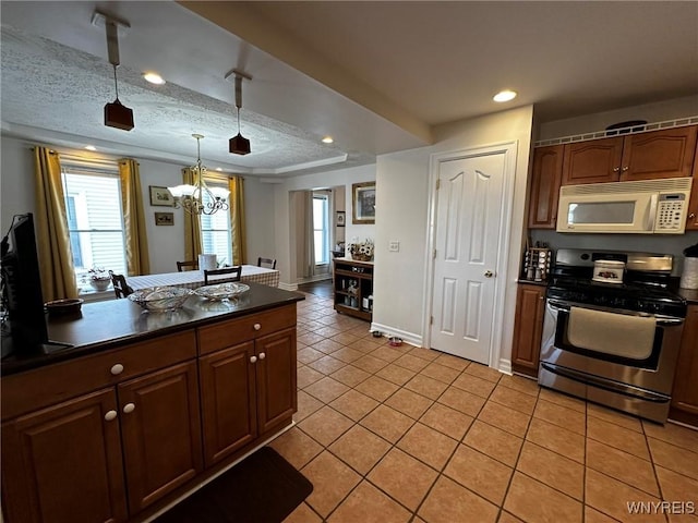 kitchen featuring light tile patterned floors, a notable chandelier, dark countertops, stainless steel range with gas cooktop, and white microwave