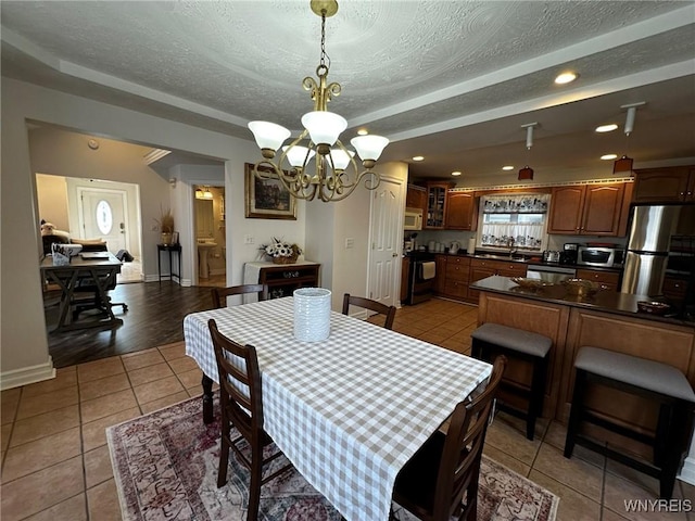 dining room with light tile patterned floors, a textured ceiling, recessed lighting, a notable chandelier, and baseboards